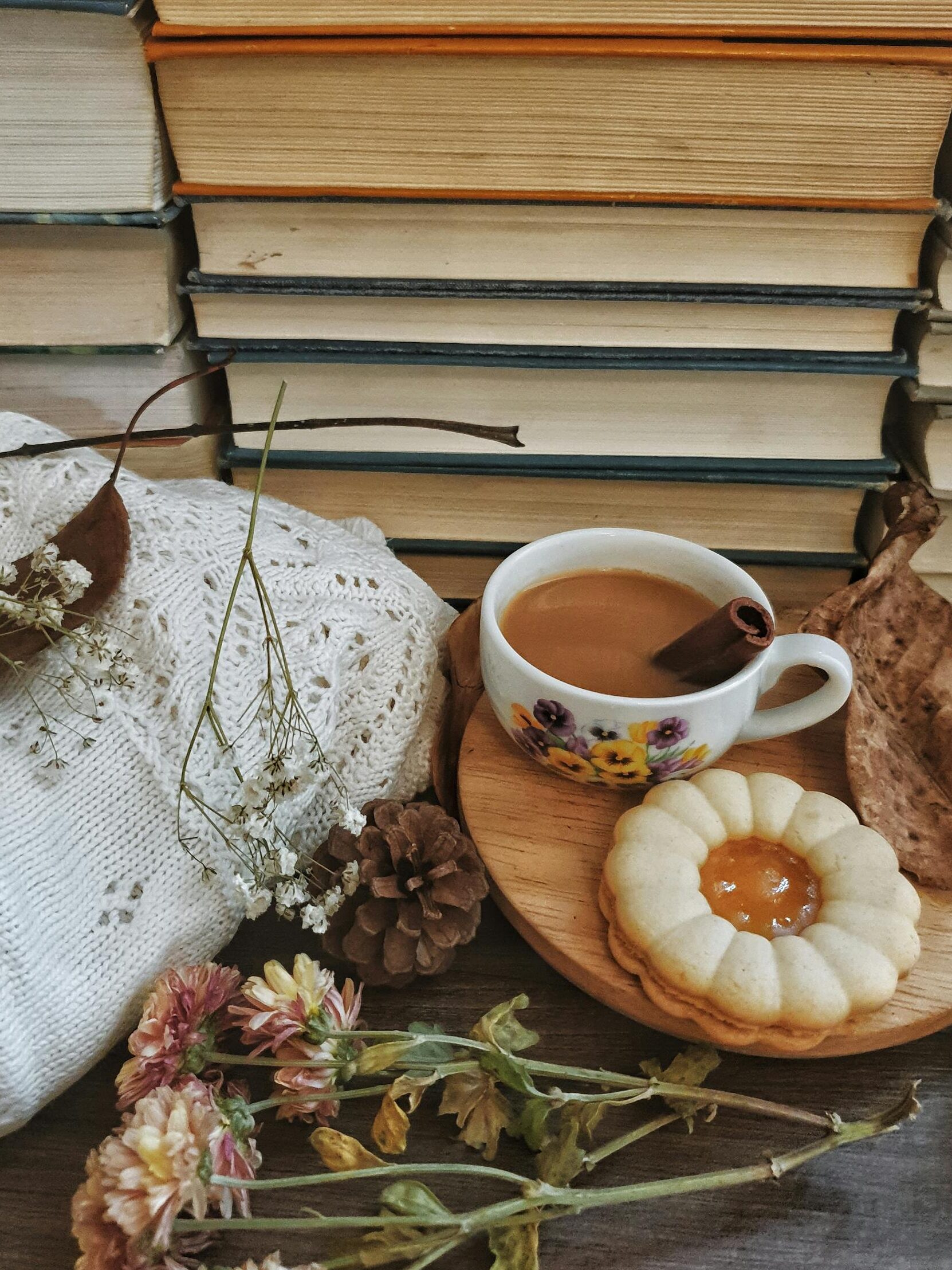Warm and inviting autumn scene featuring a coffee cup, stack of books, and cozy elements.